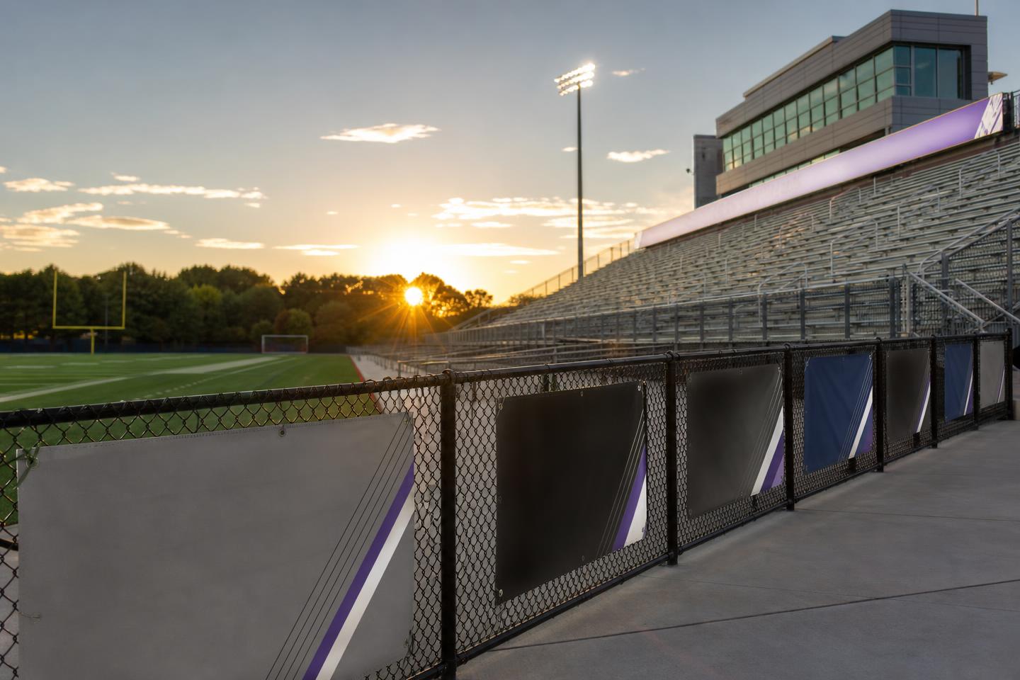Clean high school stadium with professional sponsor signage at sunset
